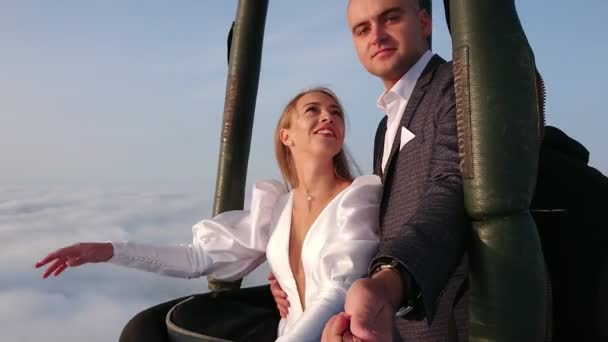 Brides fly in a balloon above the clouds. The bride and groom take a selfie stick on a balloon on a background of sunrise over the clouds. Wedding over the clouds. — Stock Video