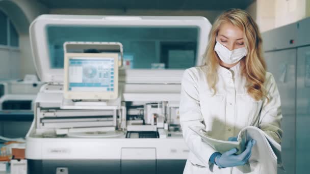Retrato de una trabajadora de laboratorio con una carpeta de investigación en sus manos. Ladorant revisa los registros de investigación en la revista. Laboratorio para el estudio de infecciones bioquímicas del virus en la sangre. — Vídeo de stock