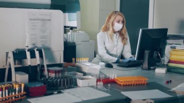 Bir mikrobiyoloji bilimadamı laboratuardaki test tüplerini kontrol eder ve bilgileri veritabanına kaydeder. Araştırmacılar kan ve mikroorganizma araştırmaları laboratuarında çalışıyorlar..
