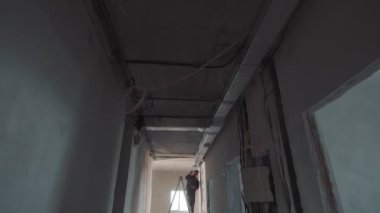 Havalandırma kanalları döşeyen bir inşaat işçisinin silueti. İnşaat alanındaki yeni bir binada merdivende çalışan bir işçi..