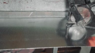 Profesyonel bir mühendis metal levha ile çalışır. Usta havalandırma kanalları oluşturmak için metal bir levhaya kesik atıyor..