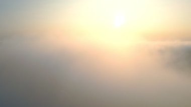 Gün batımında bulutların üzerinde uçmak. Güneş sisin üzerinden doğuyor. Sisin üzerinde turuncu gün batımı.