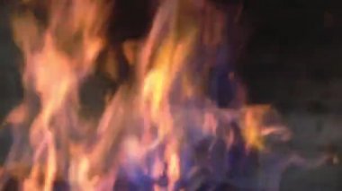 Arkaplanda barbekü ile bulanık alev var. Kıvılcımlar ve sarı-mavi parıltılar koyu bir arkaplanda.