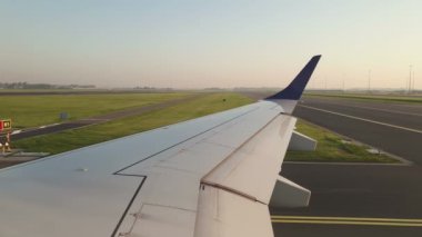 Uçağın uçuşu için hazırlanıyorum. Uçağın kanadının, pistte taksicilik yapan bir uçağın penceresinden uçağın uçuşu için hazırlanışının görüntüsü. Bir uçağın kanat manzarası