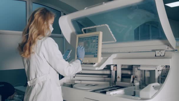 微生物学家在实验室进行研究.研究人员进行了生化分析测试。一名女性实验室工作人员使用生化分析仪器. — 图库视频影像