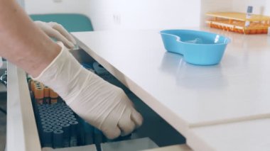 Kan test tüplerinin depolanması. Laboratuar teknisyeni test tüplerini saklamak için çekmeceyi açar ve çeşitli tıbbi aletleri ve test tüplerini çıkarır..