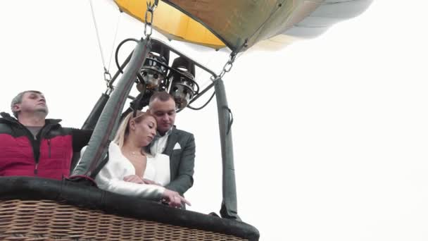 Brides fly in a balloon above the clouds. The bride and groom take a selfie stick on a balloon on a background of sunrise over the clouds. Wedding over the clouds. — Stock Video