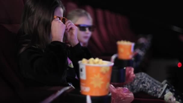 La niña sola en el cine mira la pantalla del cine. Ver una película de niños o dibujos animados en el cine. — Vídeo de stock