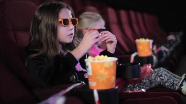 Little girl alone in the cinema looks at the cinema screen. Watching a childrens movie or cartoon in the cinema. — Stock Video