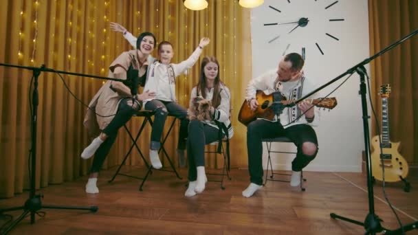 Nagy boldog család énekel, és apa gitározik. Egy boldog család egy családi körben énekel és ölelget egy dalt.. — Stock videók