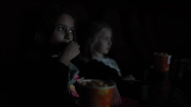 Kafkasyalı bir kız sinemada kız kardeşi arka plandayken film ya da çizgi film izliyor ve patlamış mısır yiyor. Sinemadaki kız patlamış mısır yiyor.