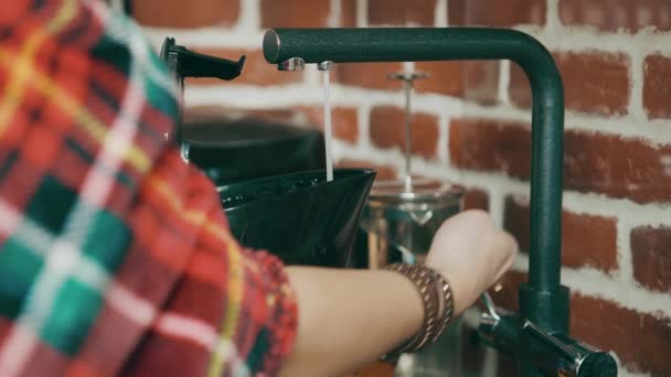 Woman who collects purified water in an electric kettle. A stream of water flows from the tap into the kettle. — Stock Video