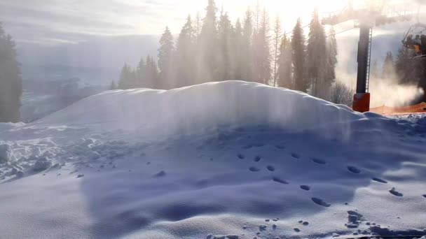 Schneekanonen in einem Skigebiet. Beschneiungsmaschinen produzieren Kunstschnee vor dem Hintergrund von Sonnenlicht und Skiliften. Herrliche Aussicht auf die Schaffung von Kunstschnee. Die Arbeit der Skigebiete. — Stockvideo