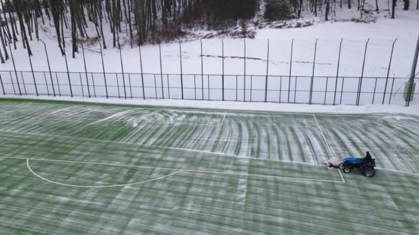 Oczyszczanie boiska ze śniegu. Śnieg pada na boisku. Maszyna czyszcząca śnieg na boisku do piłki nożnej. Przygotowanie boiska do piłki nożnej na mecz zimą — Wideo stockowe