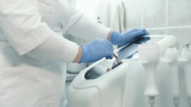 Bir güzellik salonunda cilt gençleştirme için yenilikçi bir cihazın dokunmatik ekranına bir stil bastırarak elinizi kapatın.