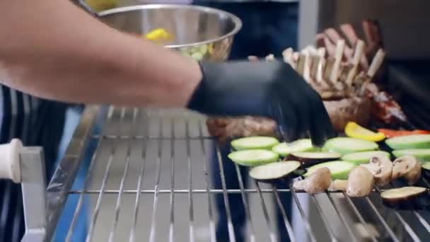 Zöldséget sütök a grillen. A séf gombát, paprikát, padlizsánt terít a grillre, hogy húsdarabokkal süssön.. — Stock videók