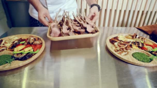 Chef demonstreert een lamsschotel samen met groenten, tomaten en groenten. close-up van een man zet een klaar gastronomisch vlees schotel op de tafel. — Stockvideo