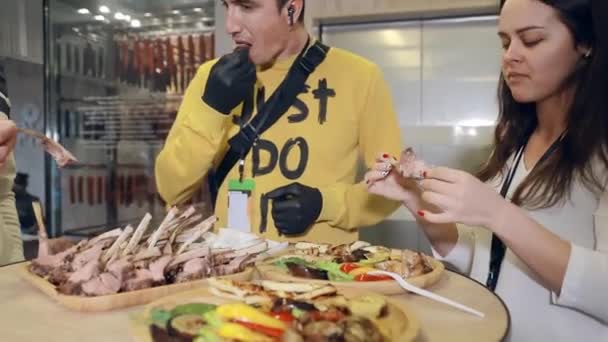 우크라이나. 리비우 25 . 12 . 2020 현지 슈퍼마켓에서 양고기를 맛보는 사람들 이다. 요리사들이 한 무리의 사람들에게 고기 시음을 했습니다. 세 사람이 한 조각의 고기를 시도하고 품질을 평가 — 비디오