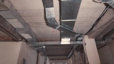 Odanın tavanında iletişim var. Teknik odanın tavanında egzoz boruları, gaz boruları ve kablo ağları var. Binanın tavanında hareket ve dağ manzarası.