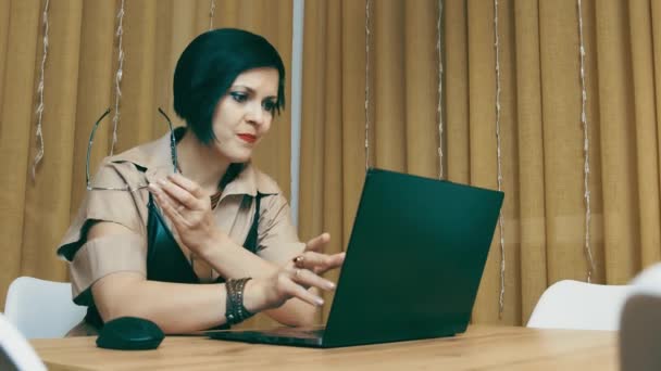 Жінка виконує роботу на ноутбуці. Дівчина закриває ноутбук, знімає окуляри і мрійливо думає. Кінець робочого дня . — стокове відео