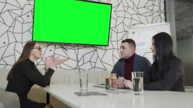 Şirket yöneticisi, şirket başkanı ve Avrupa ulusları çalışanı arasındaki ofiste konferans. Krom iskele TV ekranında. Kopyalama için yeşil arkaplan