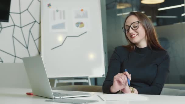 Retrato de una chica en la oficina trabajando con un portátil. Retrato de un gerente de oficina. Retrato del jefe de la empresa. Mujer sonriente — Vídeo de stock