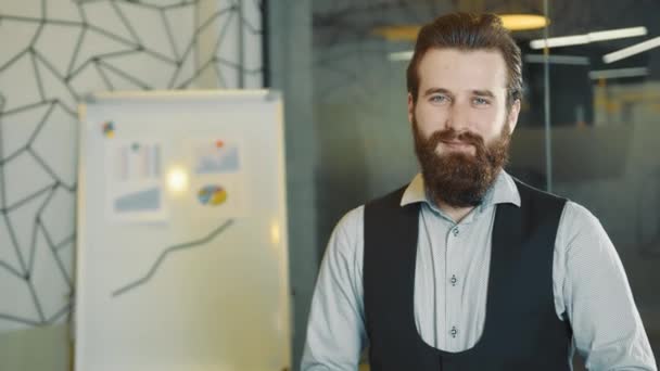 Portrait d'un employé de bureau barbu regardant la caméra. Un jeune homme d'affaires confiant. Le programmeur du bureau regarde la caméra. Des gens avec des barbes et des émotions. — Video