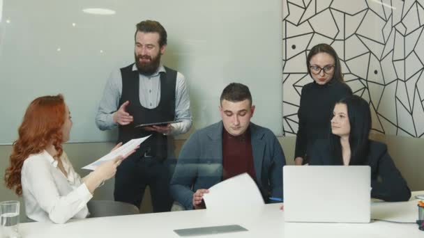 Los alegres empleados de la compañía en la oficina están sonriendo alegremente y discutiendo planes para el futuro. Un grupo de personas exitosas celebra una reunión positiva. — Vídeo de stock