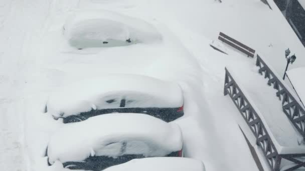 หิมะลอยในลานจอดรถ รถถูกปกคลุมไปด้วยหิมะ ดริฟท์หิมะ หิมะตกหนัก . — วีดีโอสต็อก