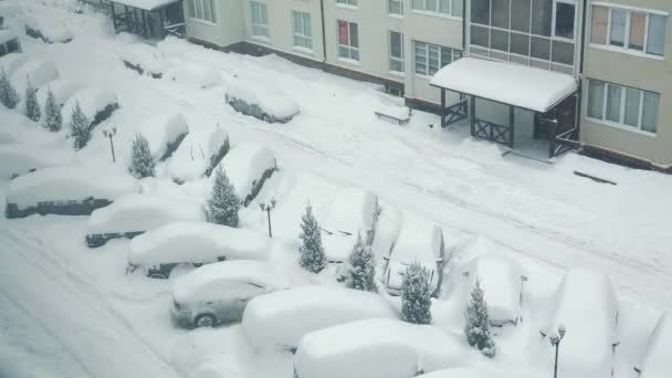 Śnieg dryfuje ulicą i samochodem. Parking i samochody na podwórku pokryte są śniegiem. — Wideo stockowe