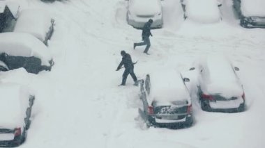 Kar kenarında park etmiş bir arabayı temizleyen bir adam. Şiddetli kar yağışıweather condition.