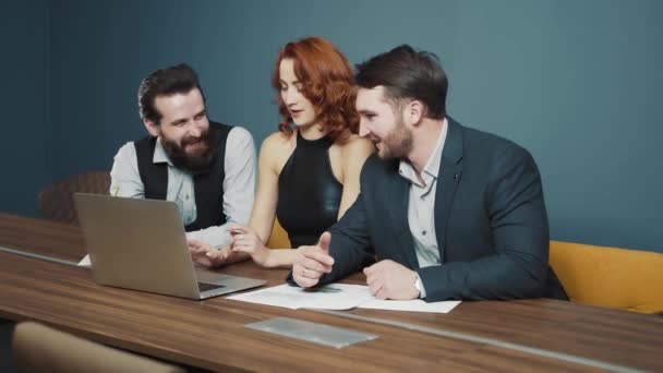 Three people of Caucasian nationality are discussing the creation of a new successful startup. Communication of men and women in the office with a laptop. People and business concept. — Stock Video