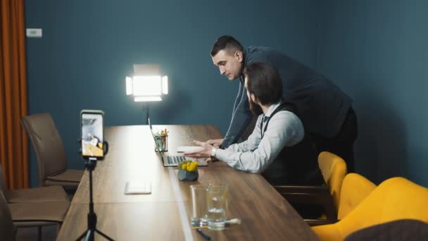 Organização de transmissão ao vivo para redes sociais. Dois homens estão a preparar-se para entrar em directo. Um pequeno estúdio improvisado com iluminação retroiluminada. — Vídeo de Stock