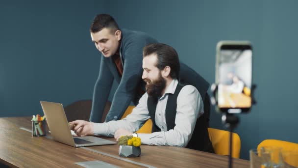 Diffuser une rencontre de deux jeunes qui discutent d'une stratégie commerciale tout en travaillant avec un cahier. Capturez une conférence sur un téléphone mobile. — Video