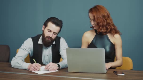 Két komoly üzletember dolgozik együtt. A nő diktálja az információt, a férfi pedig papírra veti egy tollal. Az irodai dolgozók közötti kommunikáció. — Stock videók
