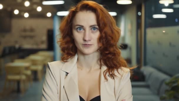 Πρόσωπο γυναίκας ευρωπαϊκής εμφάνισης με κόκκινα μαλλιά από κοντά. Μια γυναίκα με μεγάλα μπλε μάτια αναγκάζεται να κοιτάξει την κάμερα. Εστιασμένη νεαρή γυναίκα επιχειρηματίας ή διευθυντής. — Αρχείο Βίντεο