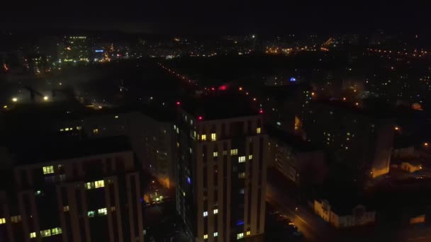 Flug über die nächtliche Stadt und das Haus, das in der Nacht leuchtet. Blick auf das Haus bei Nacht. Die Kamera fliegt zum Haus hoch. — Stockvideo