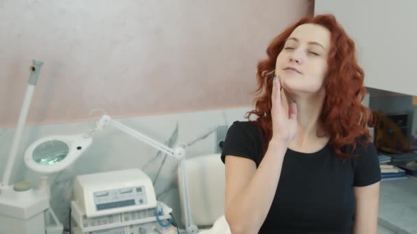 Dromerige vrouw die zachtjes raakt haar gezicht na de procedure van huidherstel en verjonging in een schoonheidssalon — Stockvideo