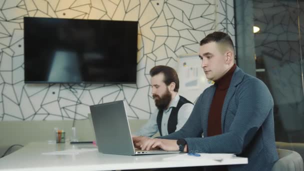 Una imagen de dos programadores trabajando en un portátil y una tableta. Programadores web en trabajo remoto. Los hombres miran a la cámara. — Vídeos de Stock