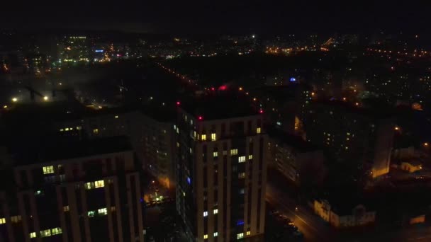 Repülés az éjszakai város és a ház felett, ami éjszaka világít. Kilátás a házra éjszaka. A kamera a házhoz repül.. — Stock videók
