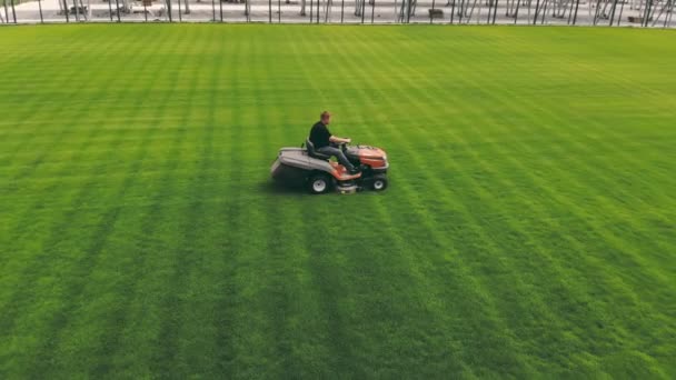 Pflege des Fußballplatzes. Ein Mann mit einem Rasenmäher mäht das Gras auf einem Fußballplatz. — Stockvideo