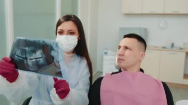 Dişçi ve hasta çenenin panoramik röntgenini inceler ve tedaviyi tartışırlar.