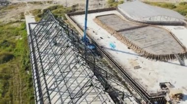 Evin çatısındaki metal yapının havadan uçuş görüntüsü. Çatısı metal olan büyük bir depo inşa ediliyor.