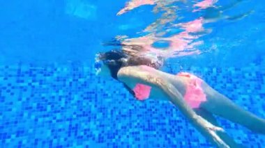 Küçük bir kız su altında yüzer ve yüzmeyi öğrenir. Suyun altındaki çocuklar için yüzme dersleri.