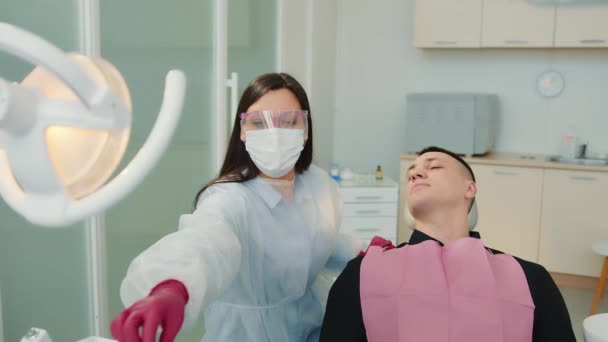 Atención dental en el consultorio del dentista. El dentista examina los dientes del paciente con una herramienta de espejo. — Vídeos de Stock