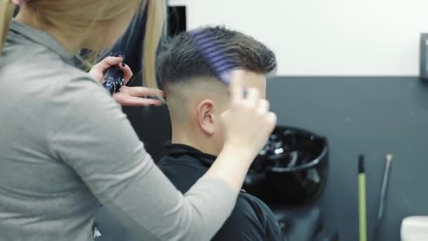 Ucrania Lviv 10.03.2021 peluquero haciendo peinado para chico joven en la barbería. Una mujer practica un corte de pelo y aprende a cortar. — Vídeo de stock