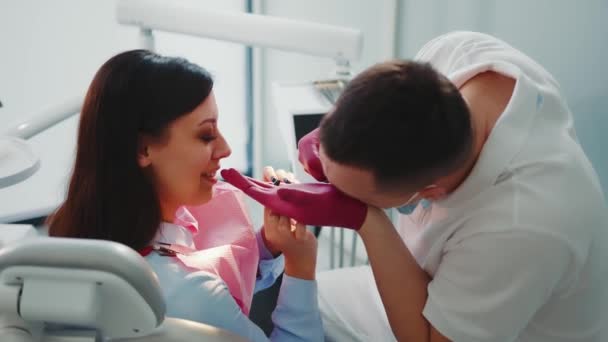 The doctor jokingly puts on small gloves. The dentist together with the patient tries to put on medical gloves. — Stock Video