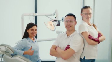 Diş hekiminin muayenehanesindeki dişçi asistanı ve hastası. Dişçilerle birlikte mutlu bir şekilde gülümsüyor. Başarılı doktorların portresi.