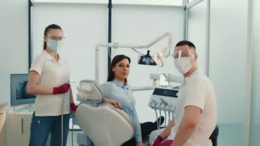 Diş hekiminin muayenehanesindeki dişçi asistanı ve hastası. Dişçilerle birlikte mutlu bir şekilde gülümsüyor. Başarılı doktorların portresi.