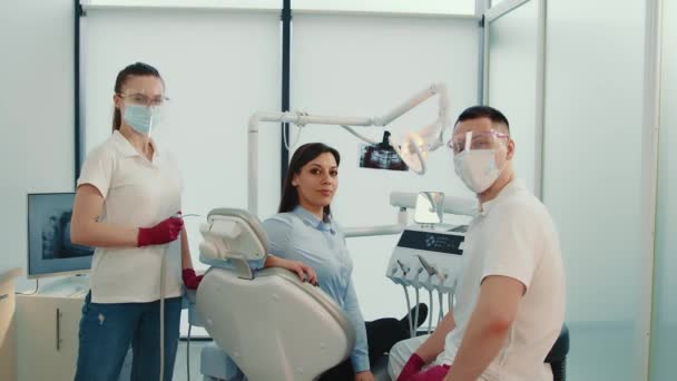 Fogorvosi asszisztens és páciens a fogorvosi rendelőben. Mosolygó elégedett beteg együtt fogorvosok. A sikeres orvosok portréja. — Stock videók